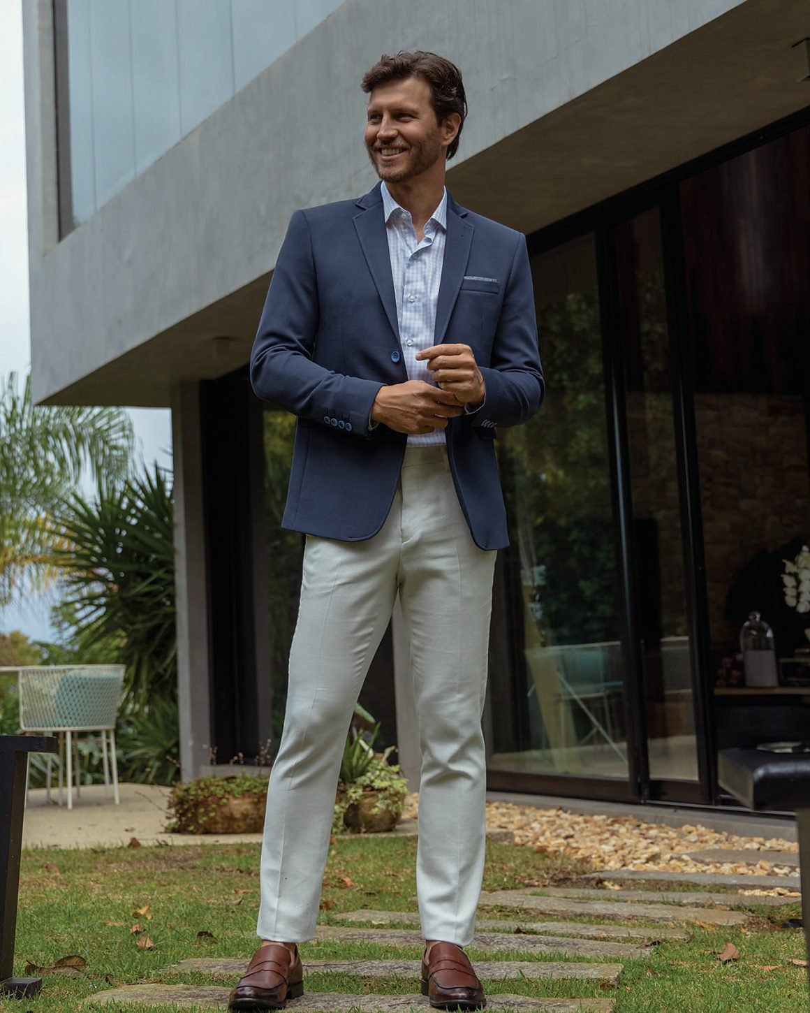 Blazer azul-marinho sobre camisola bege, junto a fachada envidraçada