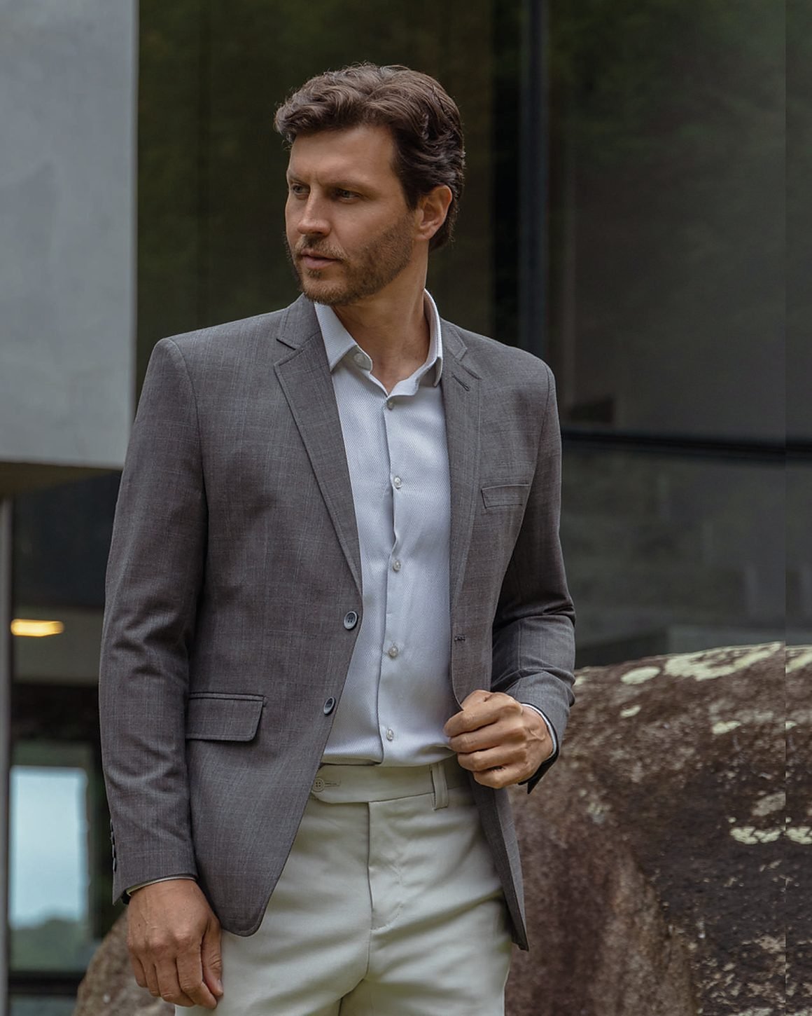 Blazer grafite sobre camisa clara, em ambiente de concreto aparente